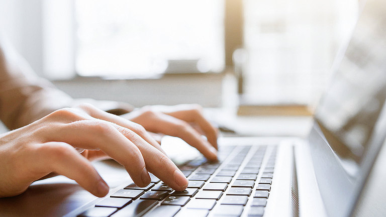 Downloads Zwei Hände tippen auf einer Laptop-Tastatur